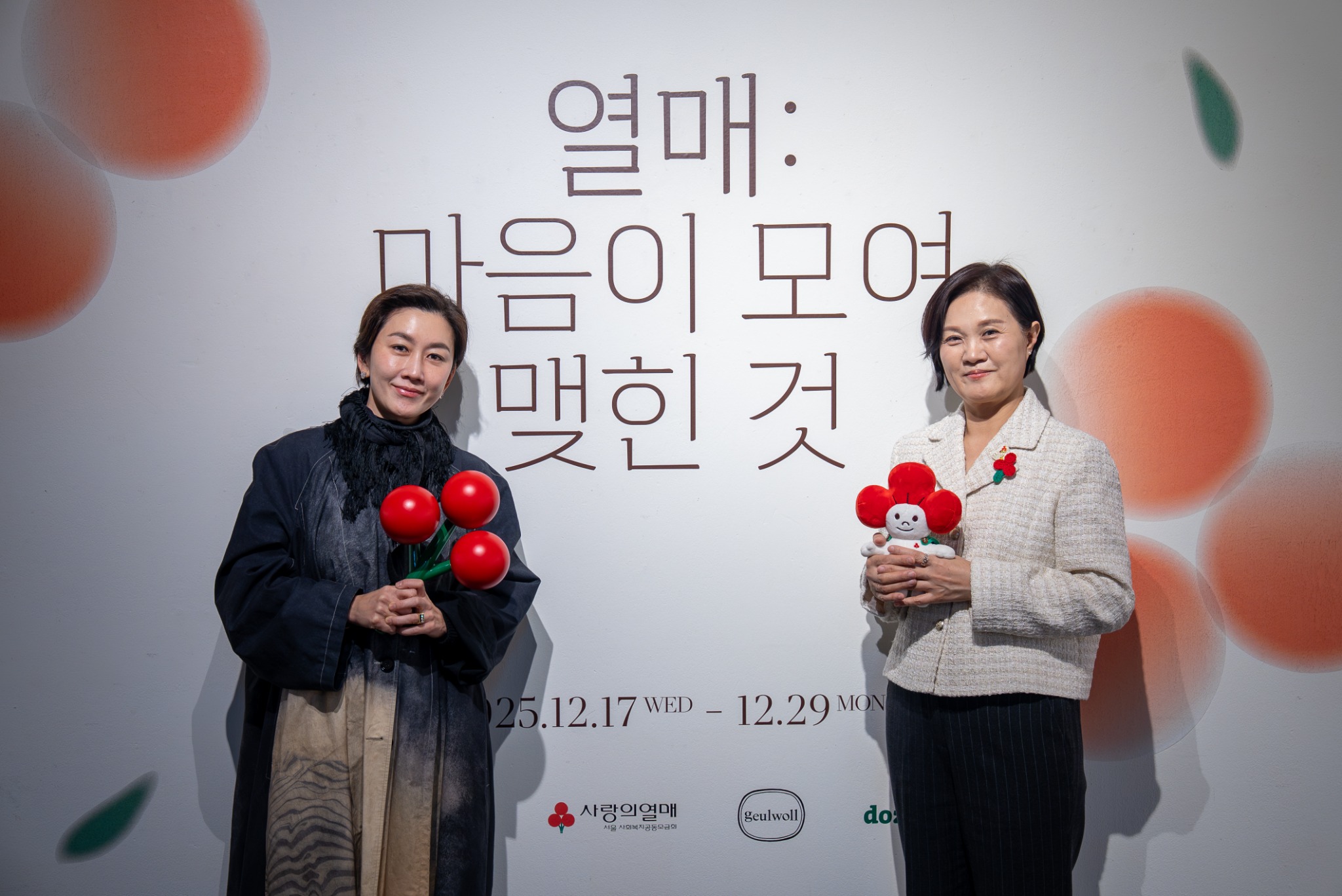프린트베이커리 사랑의열매 행사 전시 벽 앞의 두 인물